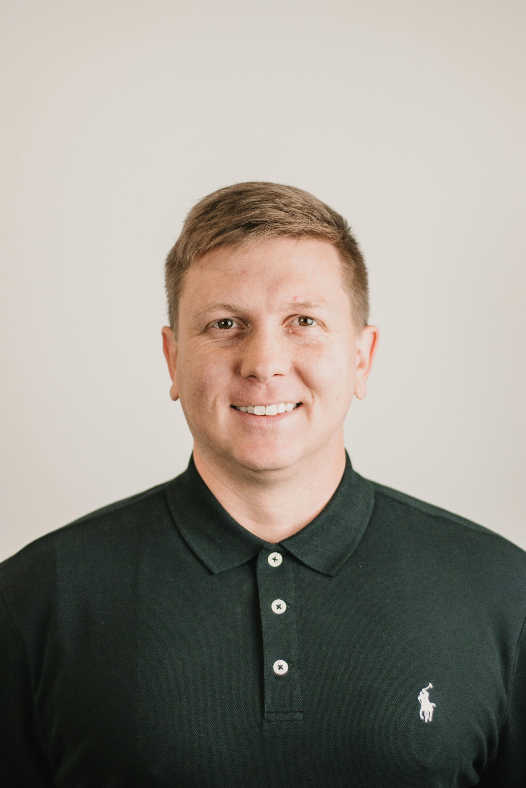 A polished headshot of a smiling man in a dark polo shirt, ideal for business or personal use.