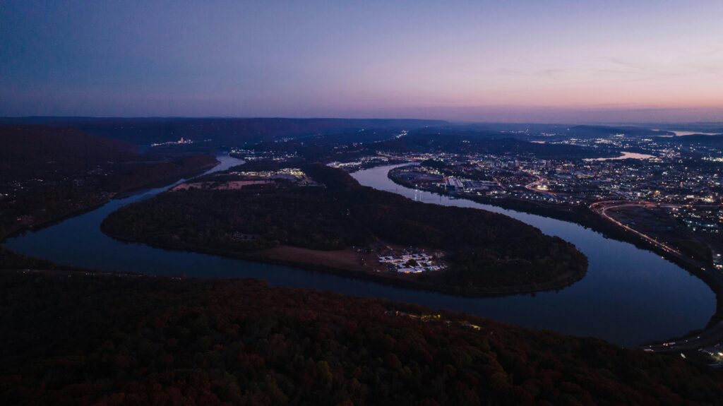 Aerial image showcasing Lookout Mountain, Tennessee, and Chattanooga River at twilight with city lights.